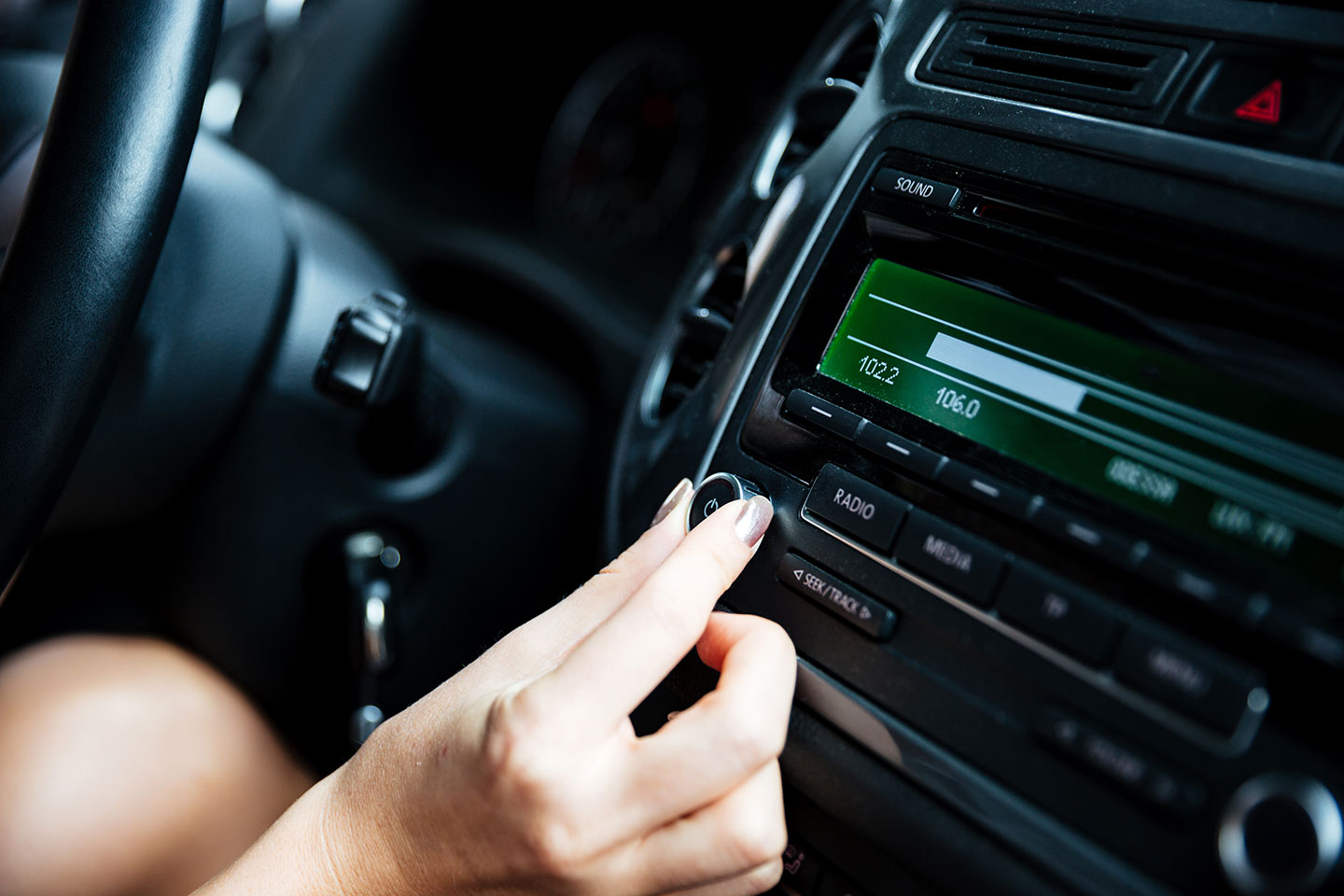 Picture of a person tuning into a radio station in the car